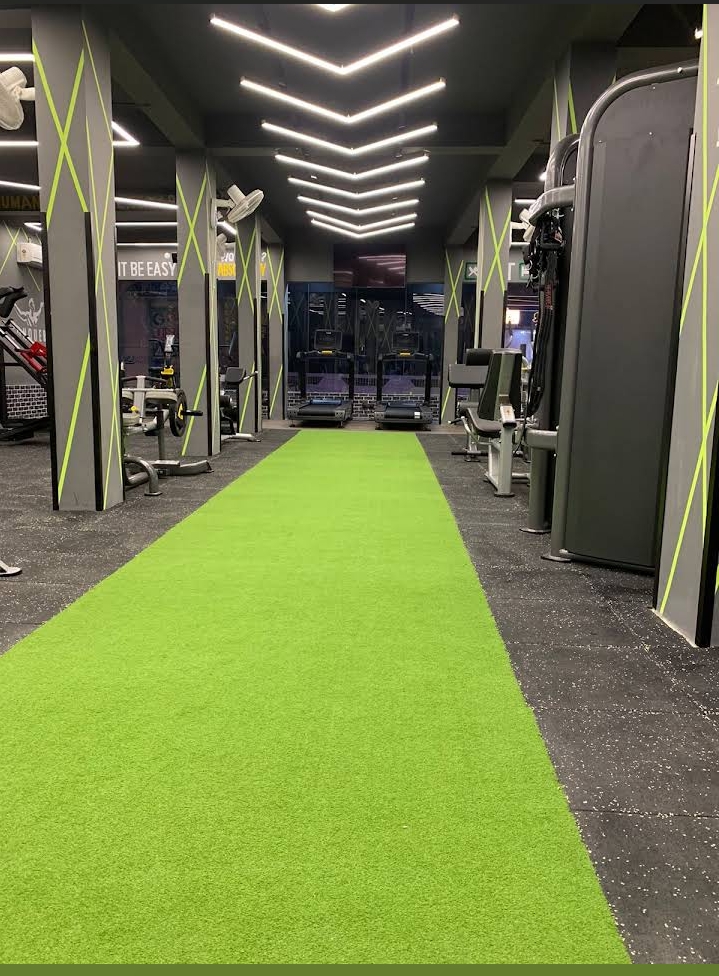 Sweatbox Gym signature neon green turf walkway with treadmills