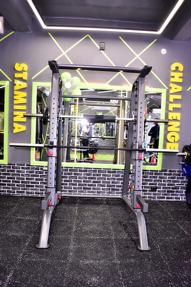 Stamina Challenge squat rack with neon green X accent wall